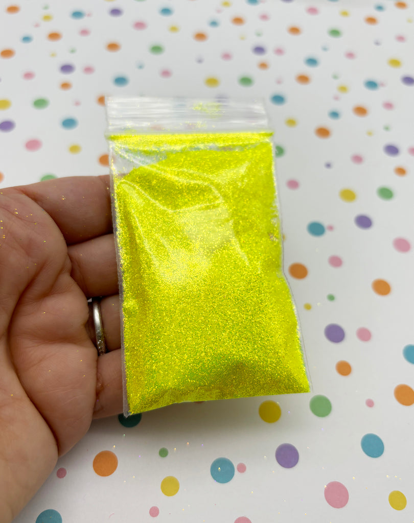 a hand holding a small yellow bag of glitter