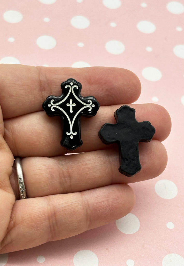 a person holding two small black and white crosses