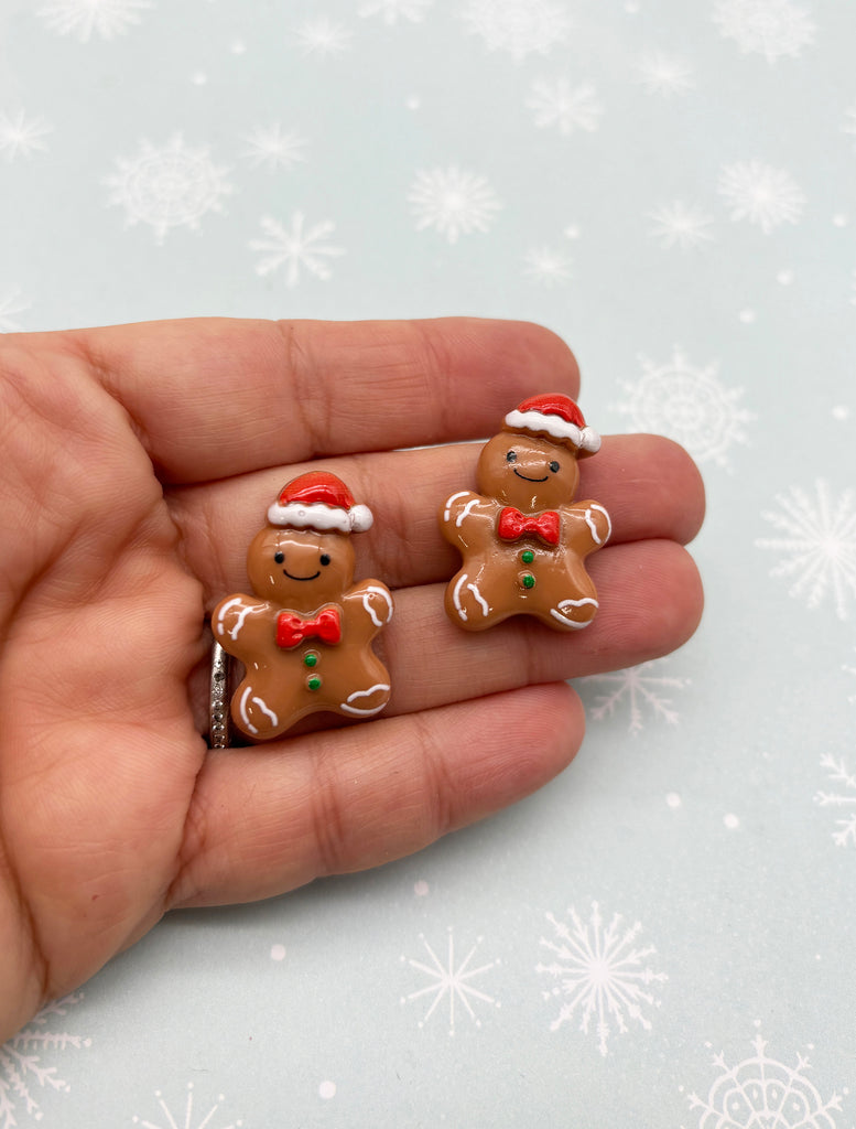 a hand holding a pair of gingerbread earrings