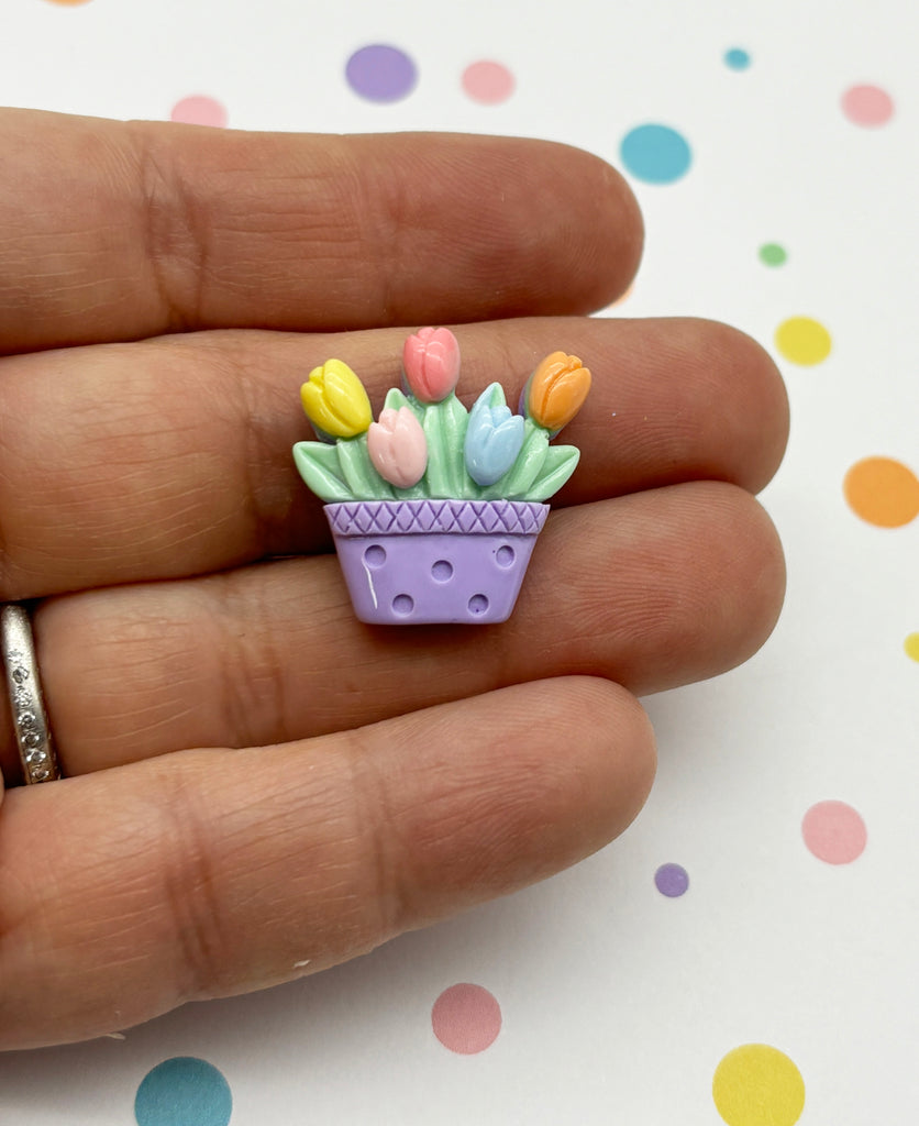 a small purple flower pot with tulips in it