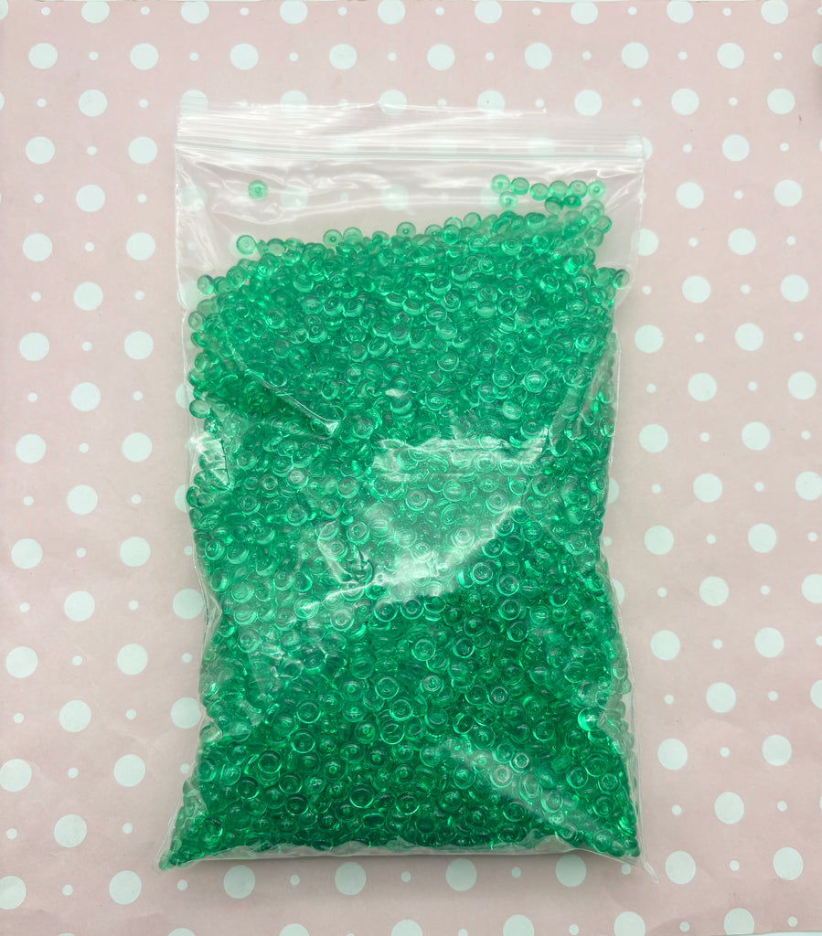 a bag of green plastic beads on a polka dot tablecloth