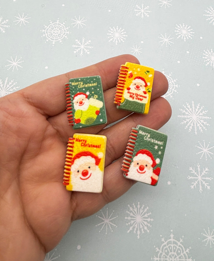 a hand holding three small christmas themed magnets