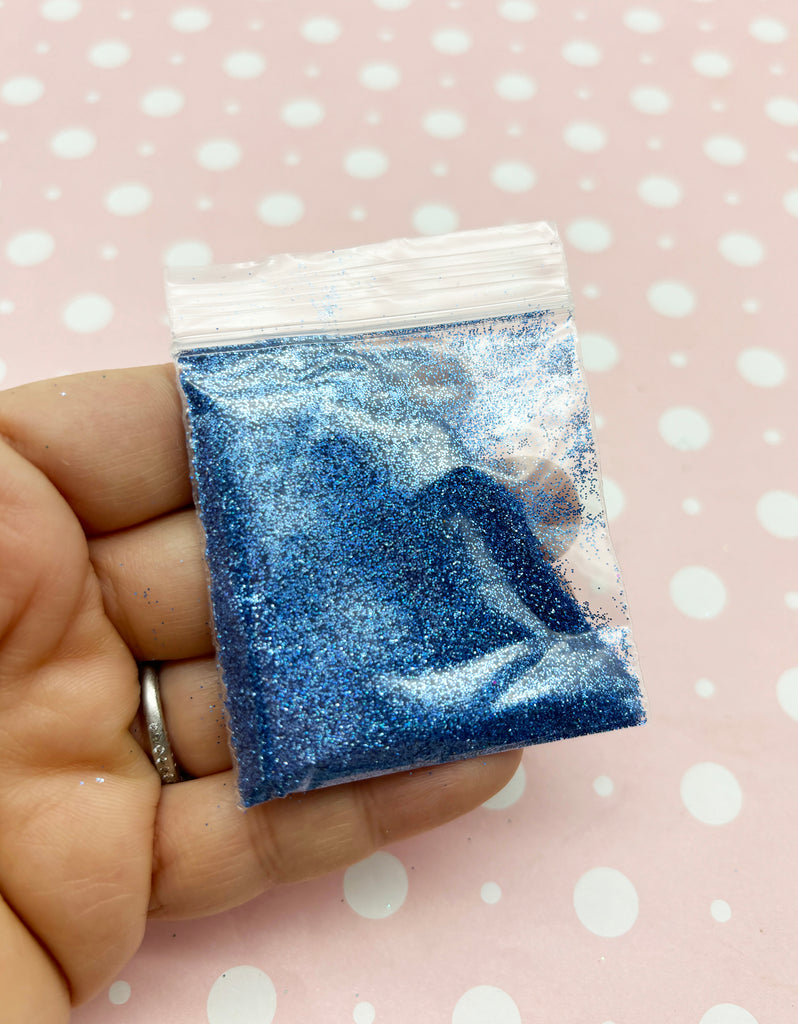 a hand holding a small bag of blue glitter