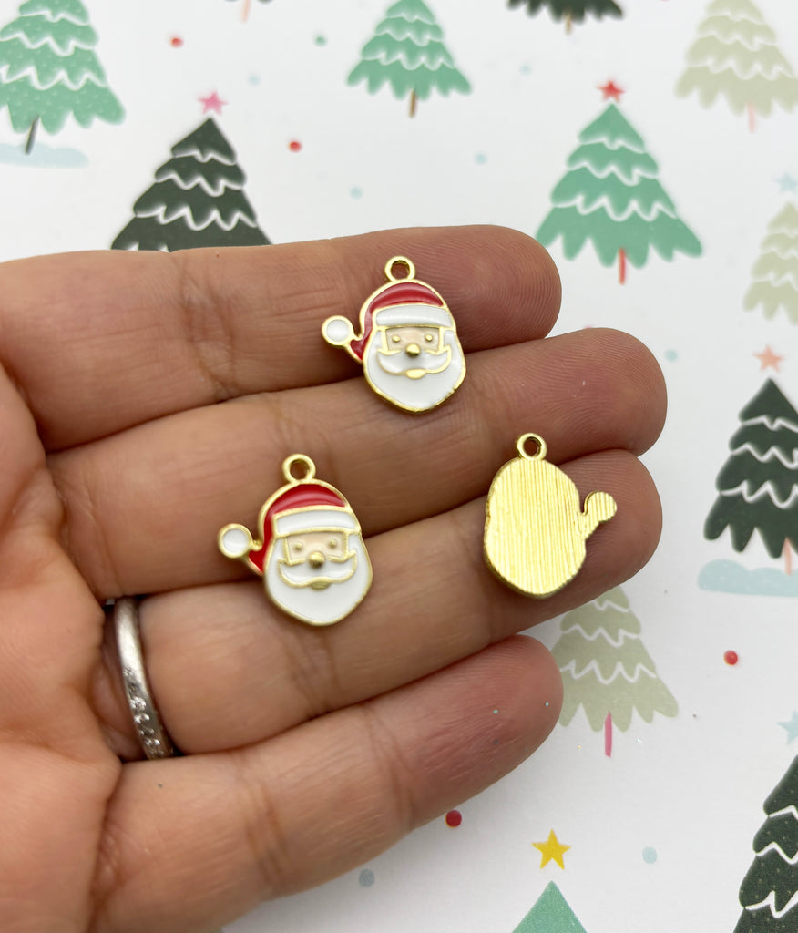 a person holding two small christmas charms in their hand