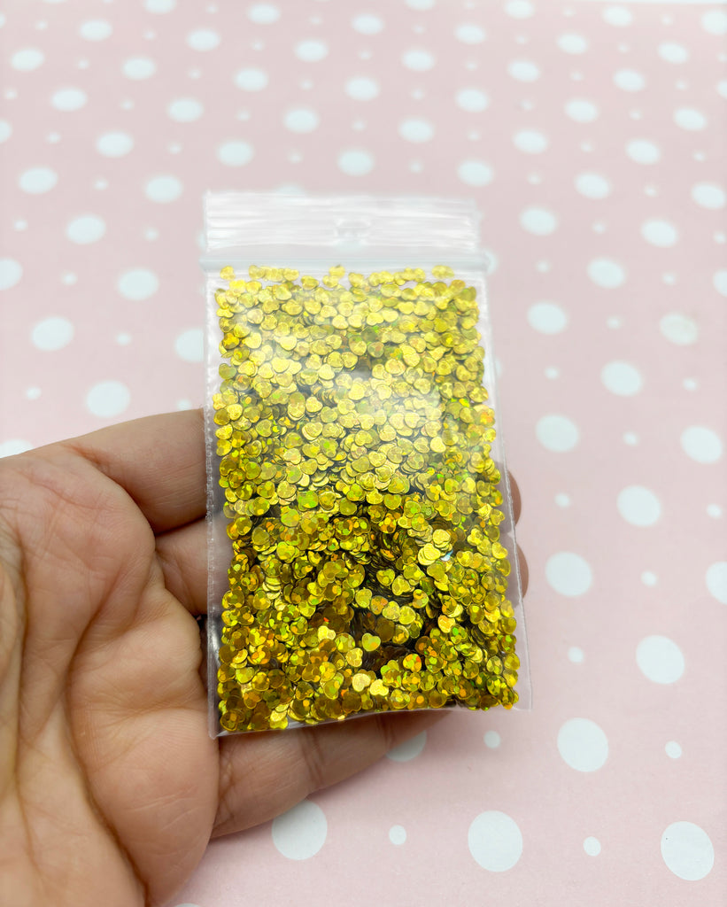 a hand holding a bag of yellow glitter