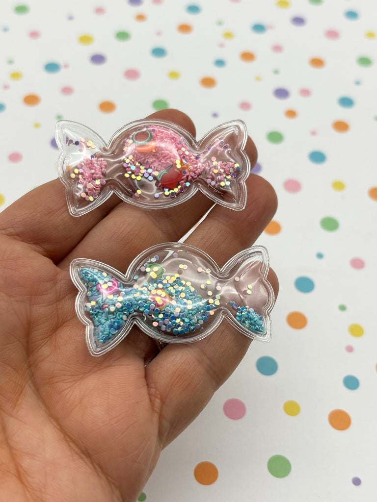 a hand holding a pair of glittered candy bows