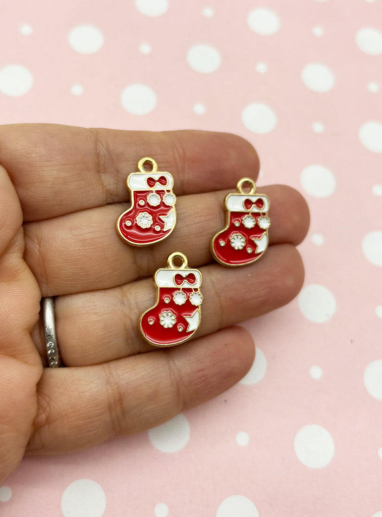 a hand holding three red christmas stocking charms