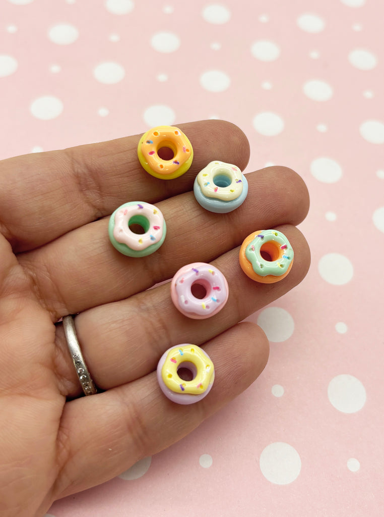 a person's hand holding five miniature doughnuts