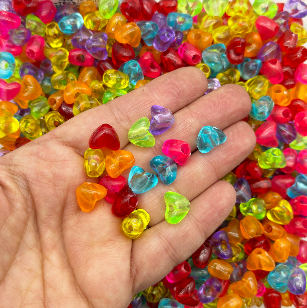 a hand holding a handful of multicolored heart shaped beads