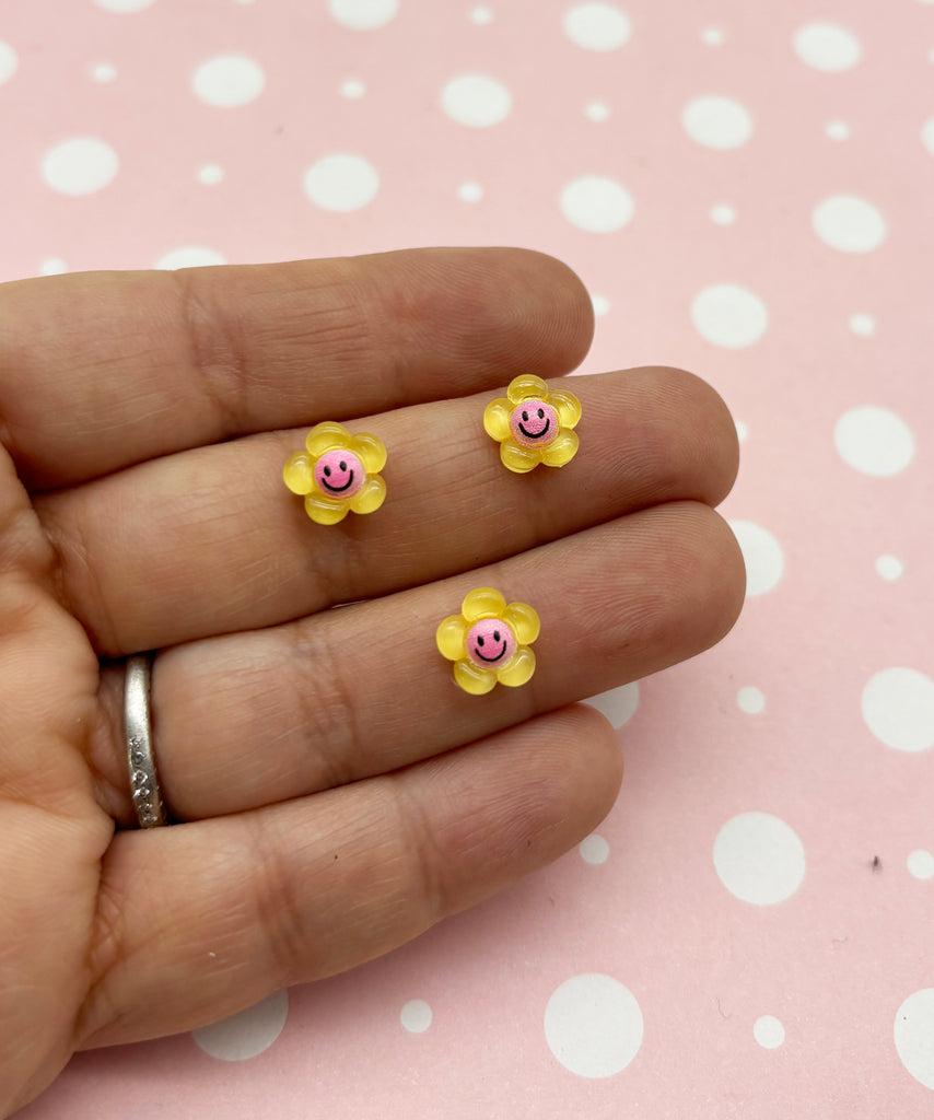 a person's hand holding a pair of tiny yellow flowers
