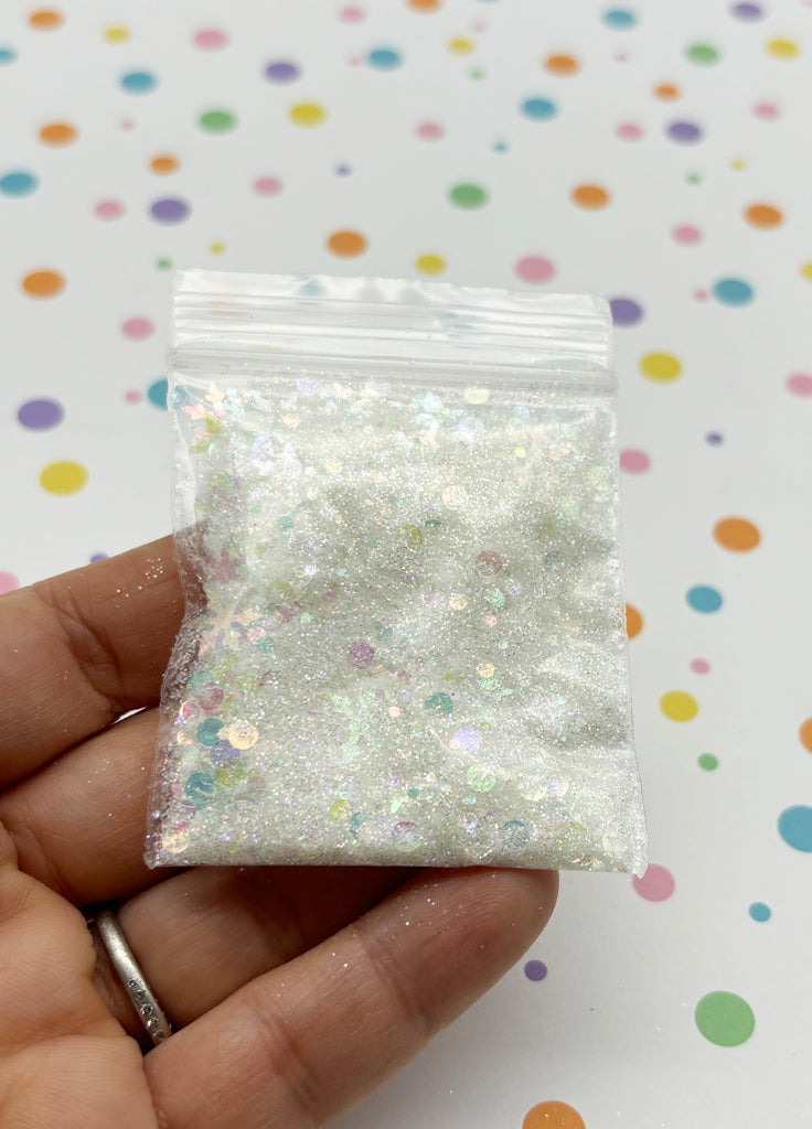 a hand holding a small bag of white glitter