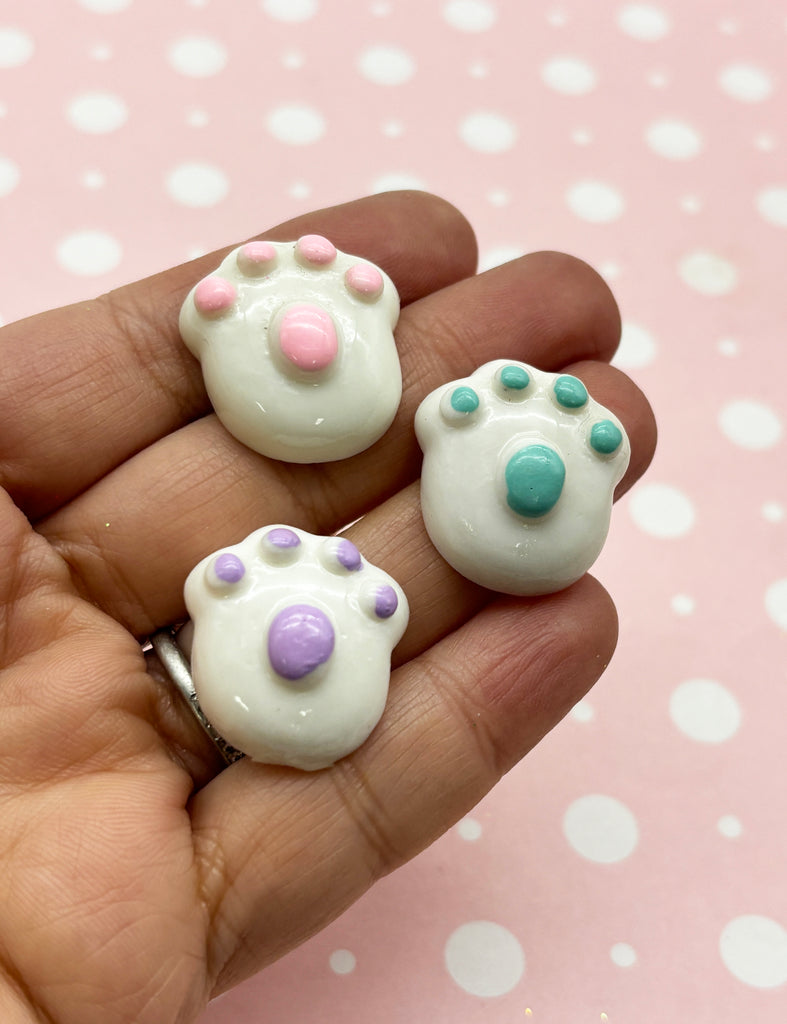 a hand holding three small white and pink bears