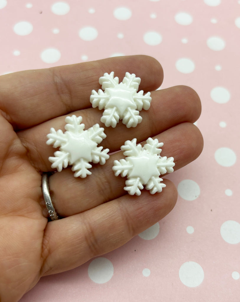 a person is holding three snowflakes in their hand