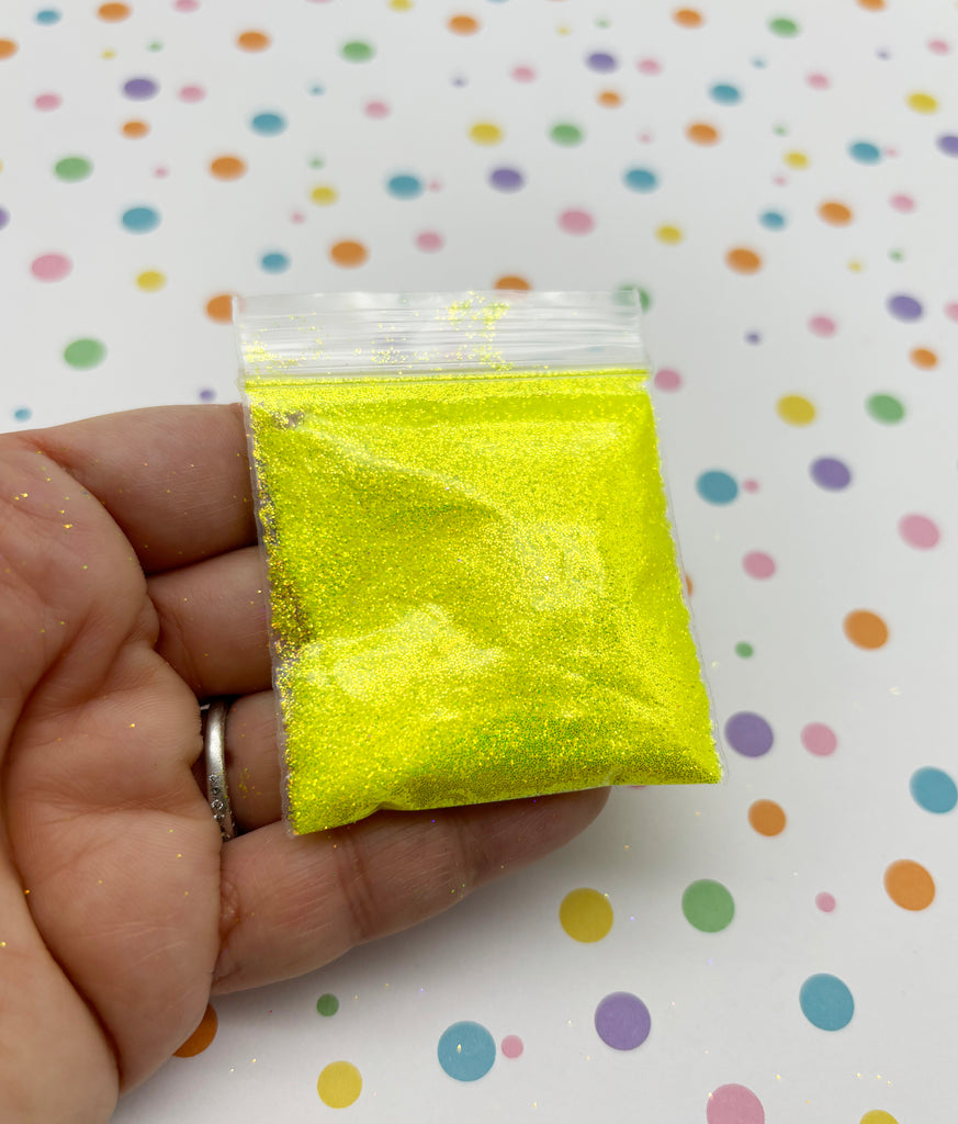 a hand holding a small bag of yellow glitter