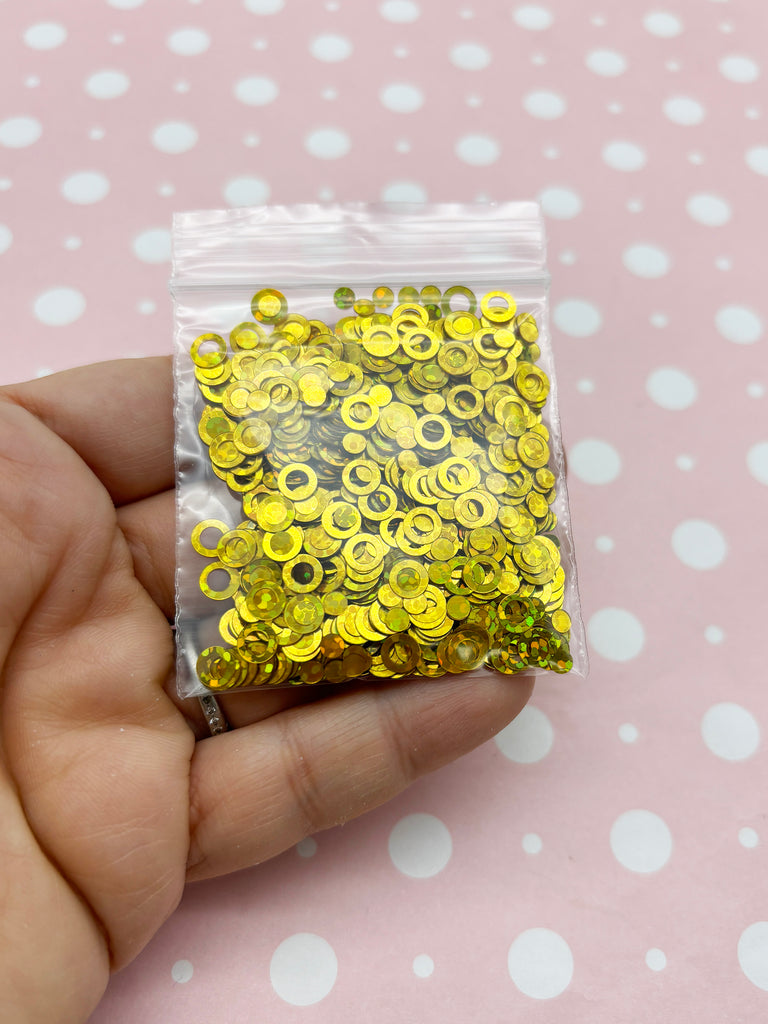 a hand holding a bag of yellow sequins
