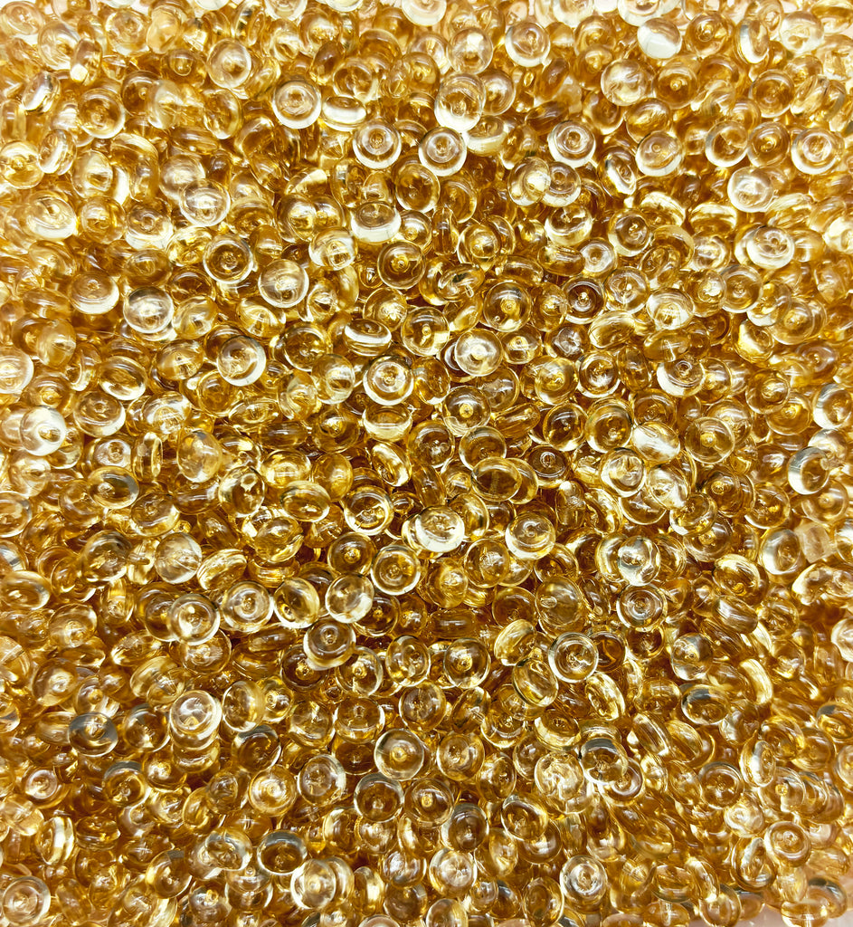 a pile of gold colored beads on a white surface