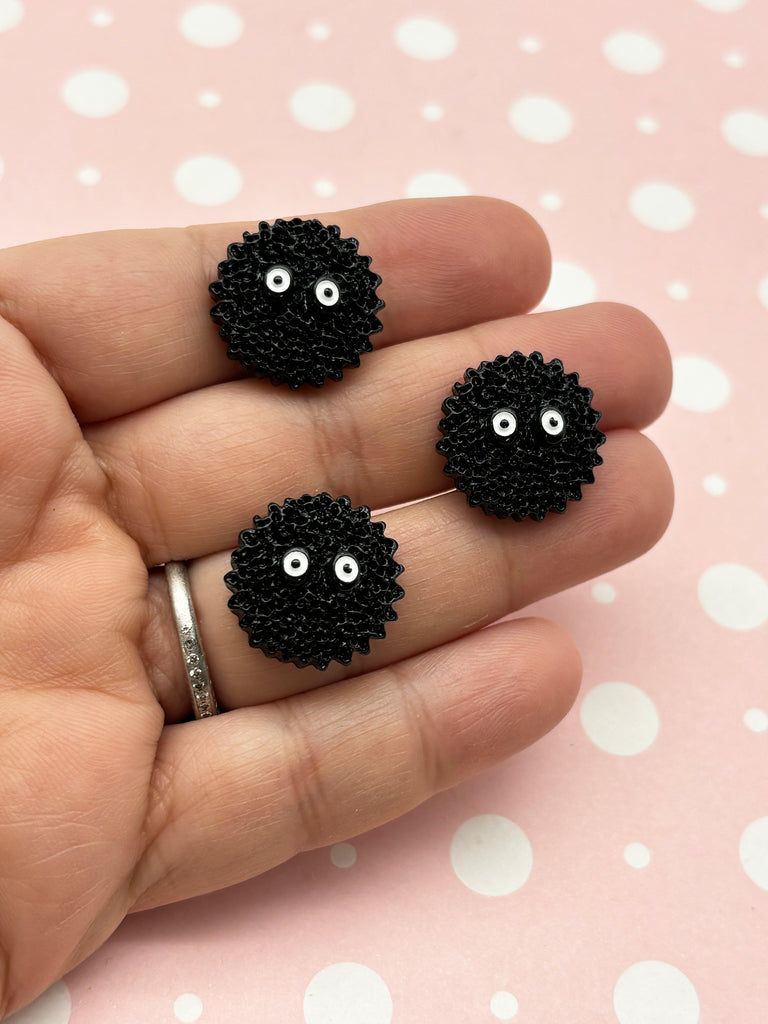 a hand holding two black beads with eyes