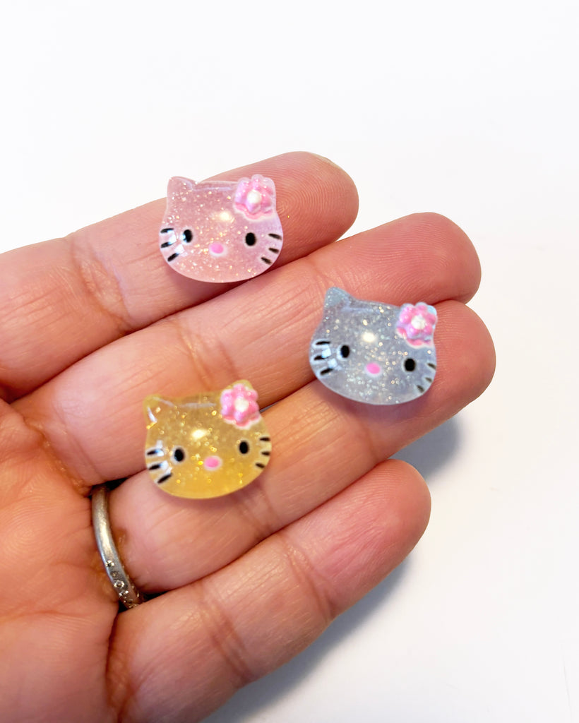 a person holding two small kitty shaped rings