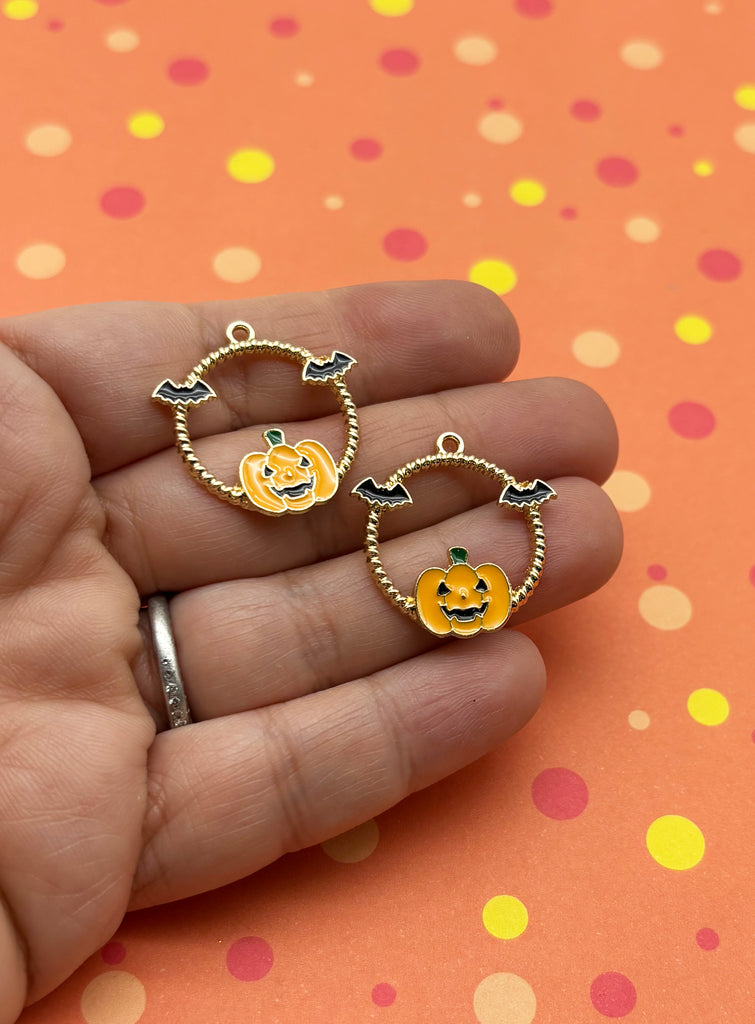 a hand holding a pair of pumpkin earrings