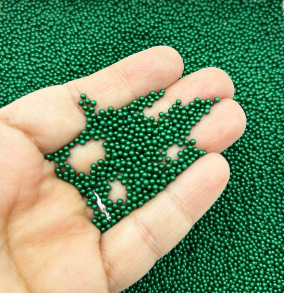 a hand holding a green beaded snowflake