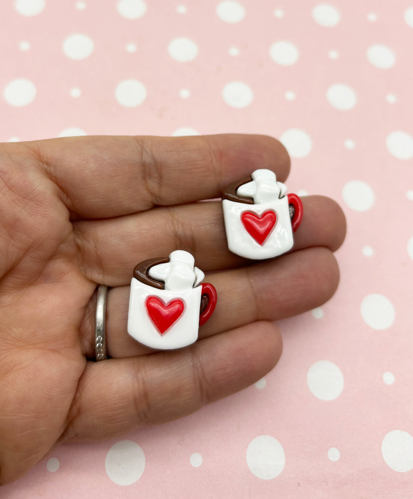 a hand holding a pair of heart shaped rings