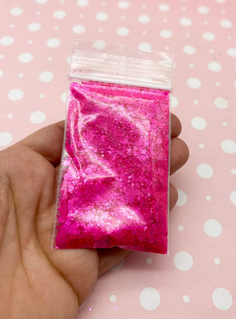 a hand holding a bag of pink glitter