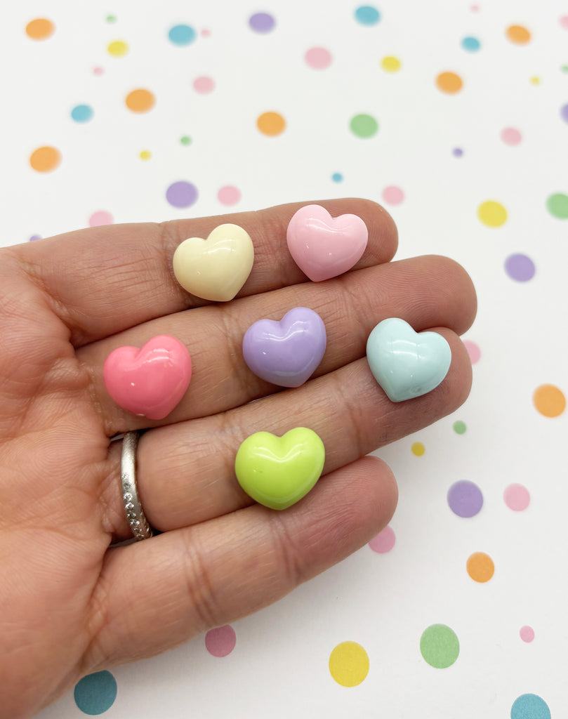 a person's hand holding four small hearts