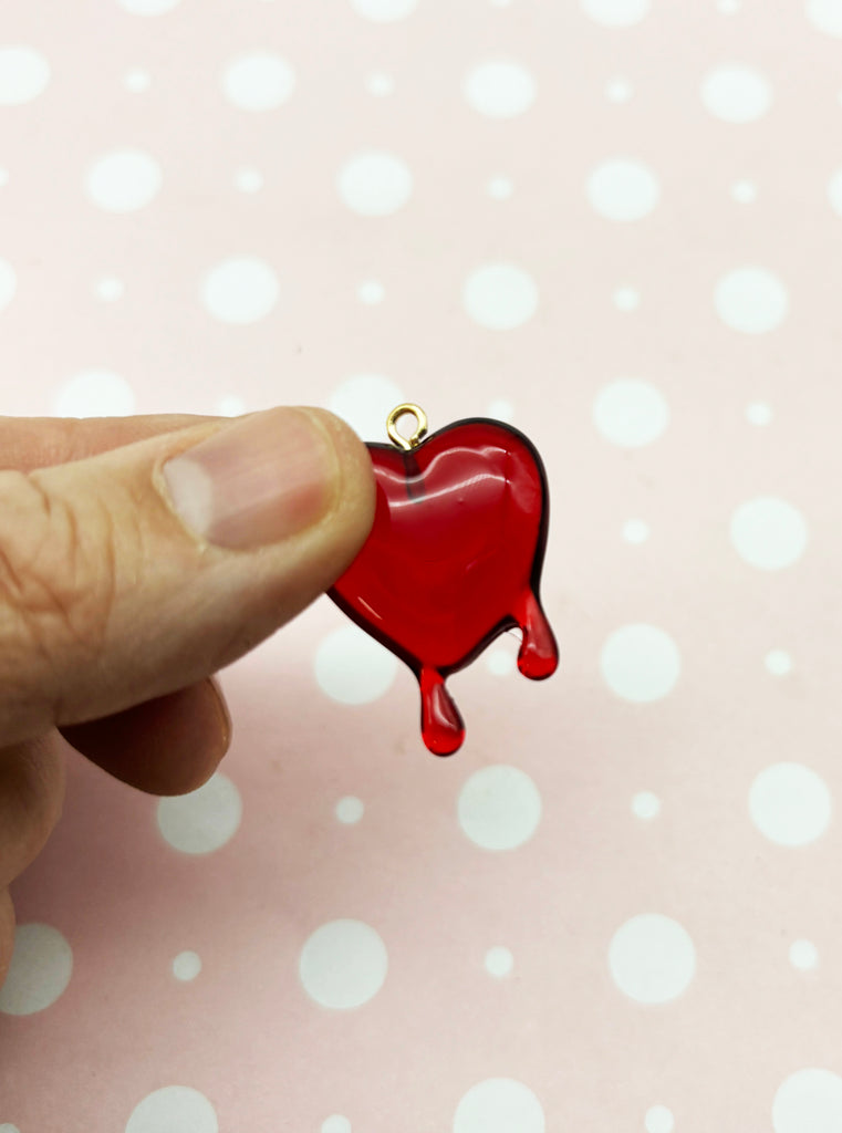 a hand holding a red heart shaped pendant