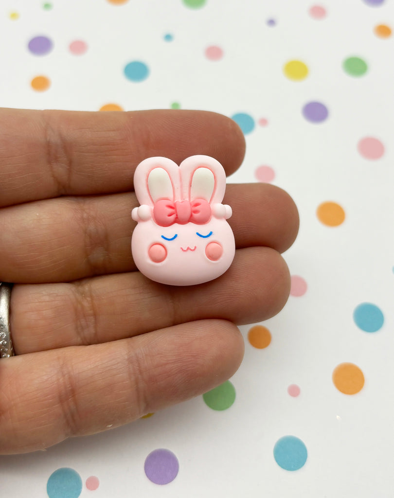 a person holding a tiny pink bunny brooch in their hand