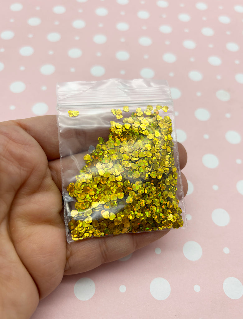 a hand holding a bag of gold glitter