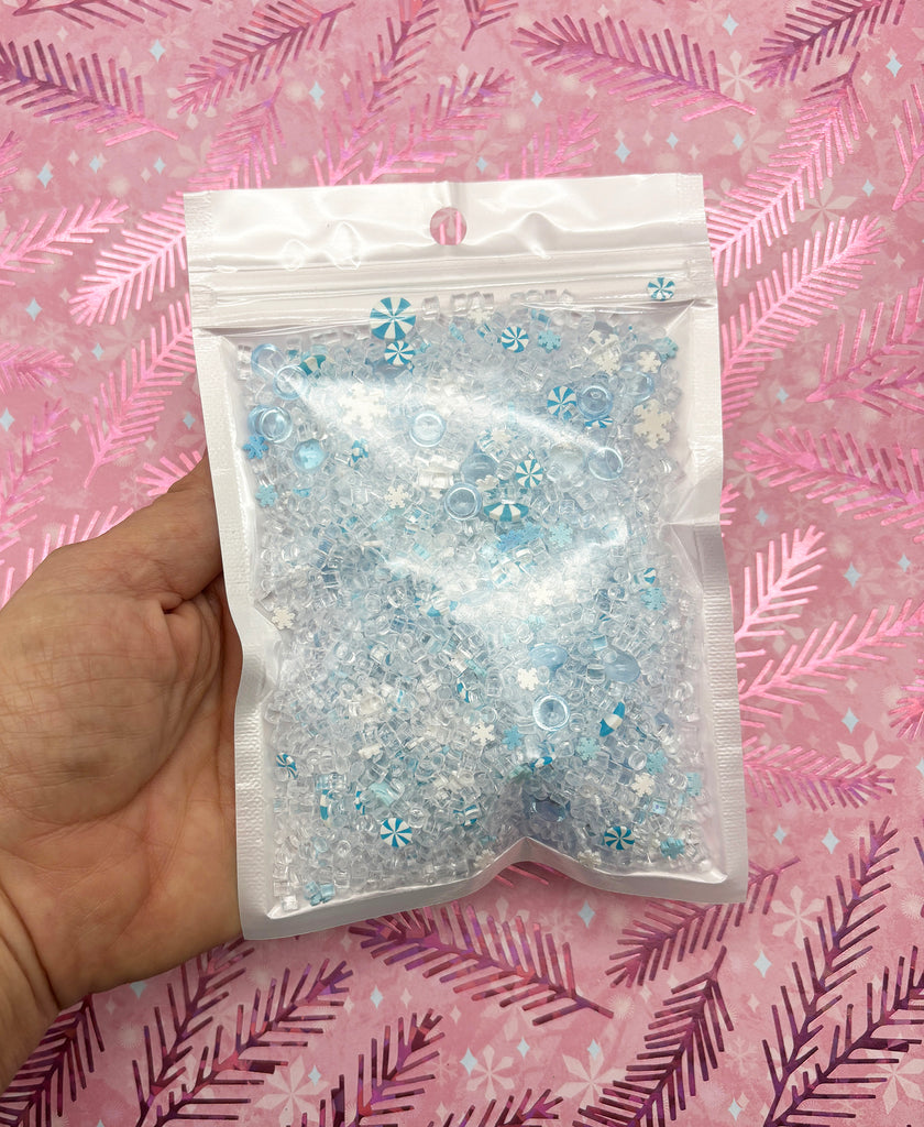 a hand holding a bag of blue and white glitter