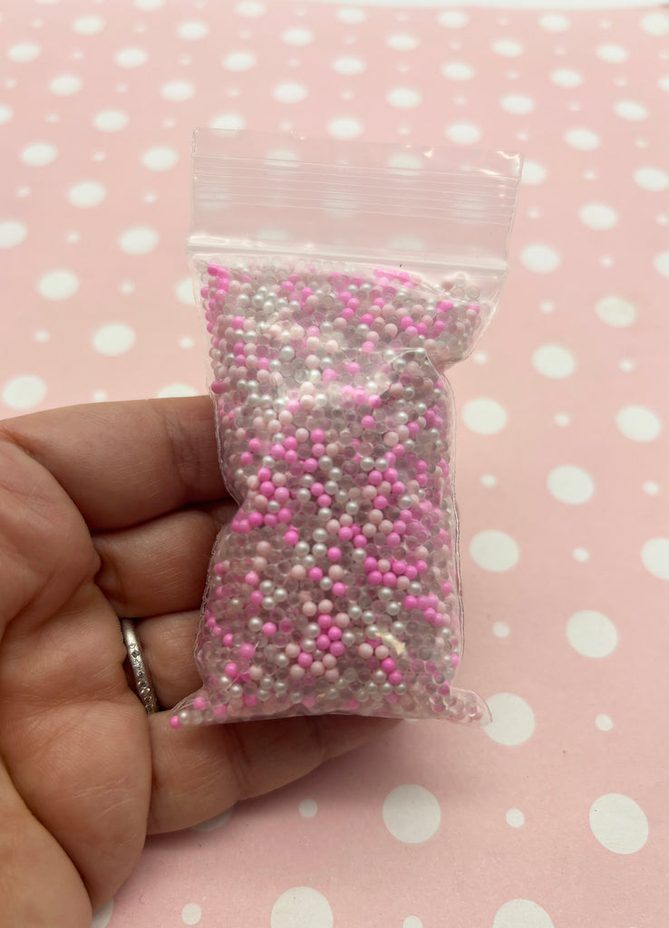 a hand holding a bag of pink and white sprinkles