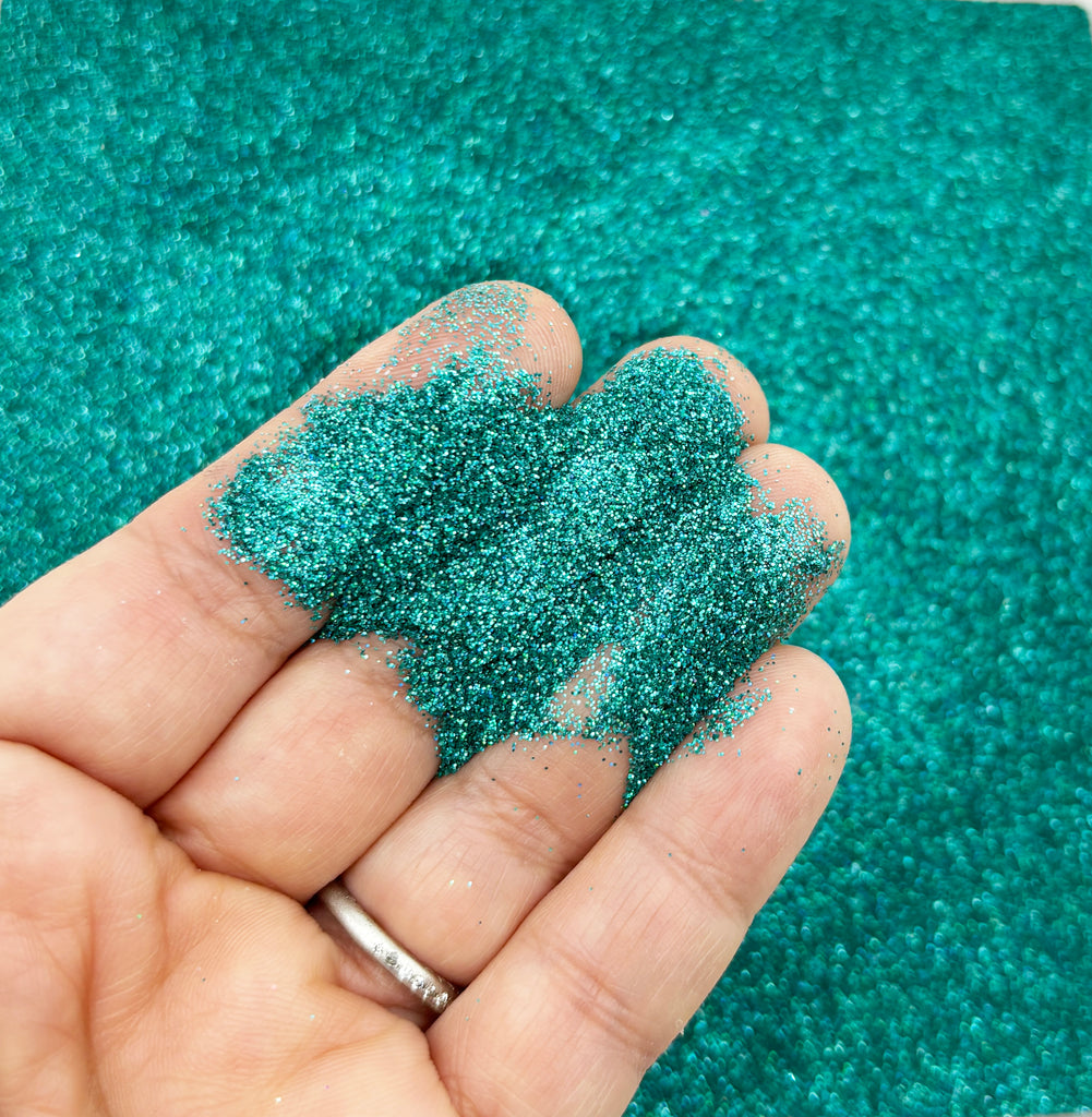 a hand holding a pile of green glitter