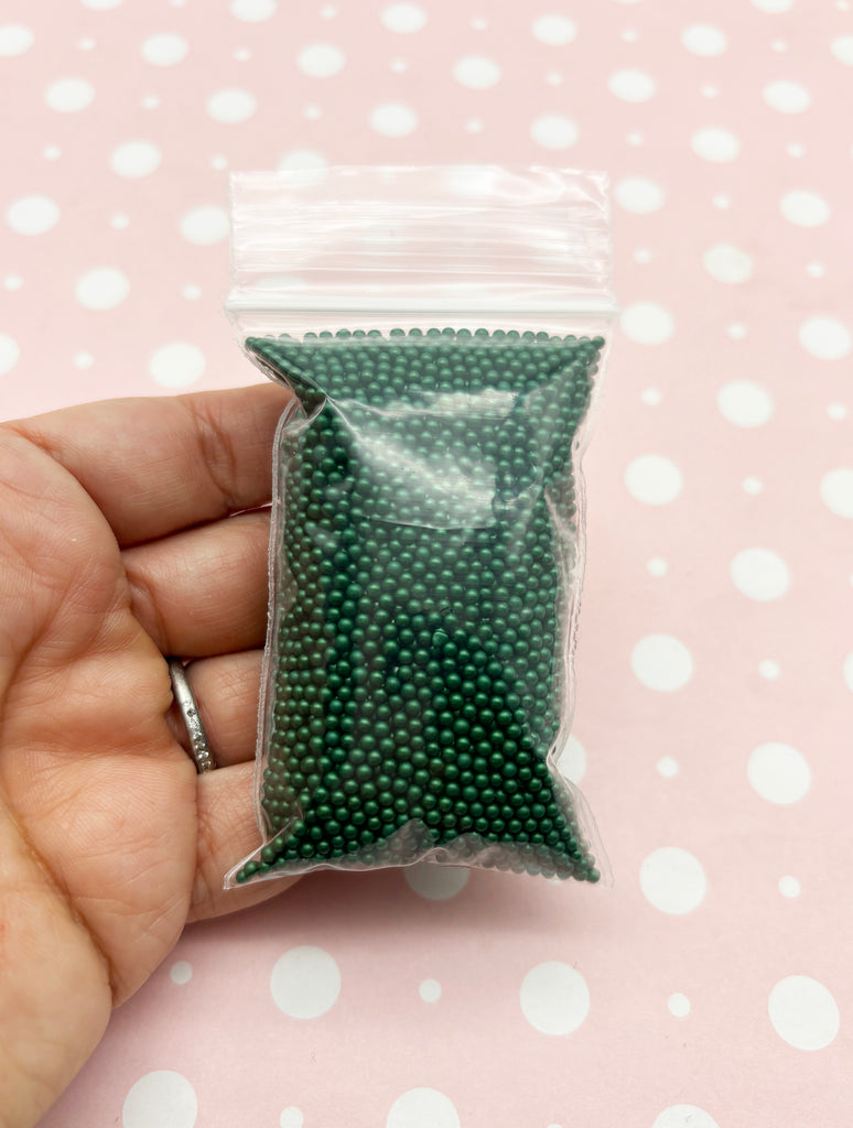 a hand holding a bag of green beads