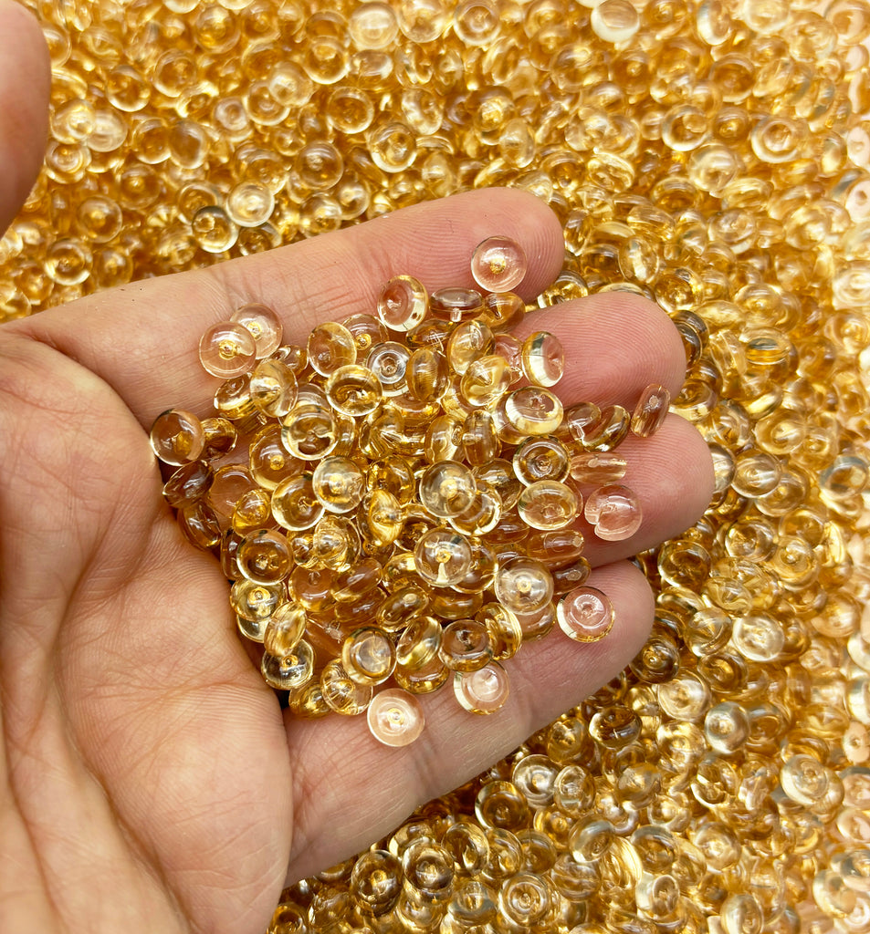 a person holding a handful of gold colored beads