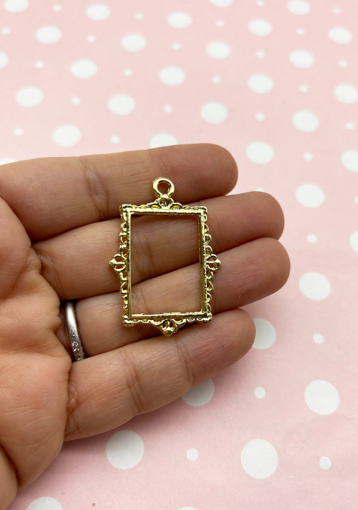 a person is holding a small square pendant in their hand