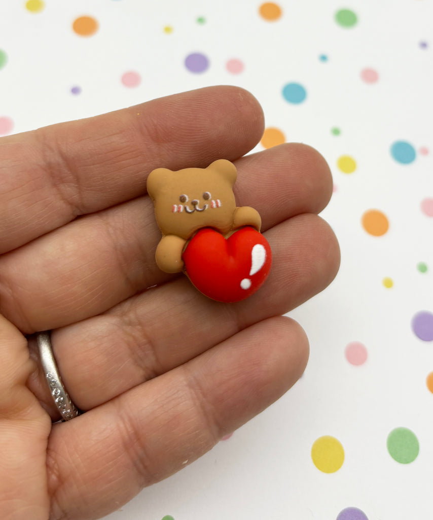 a tiny teddy bear holding a heart shaped object