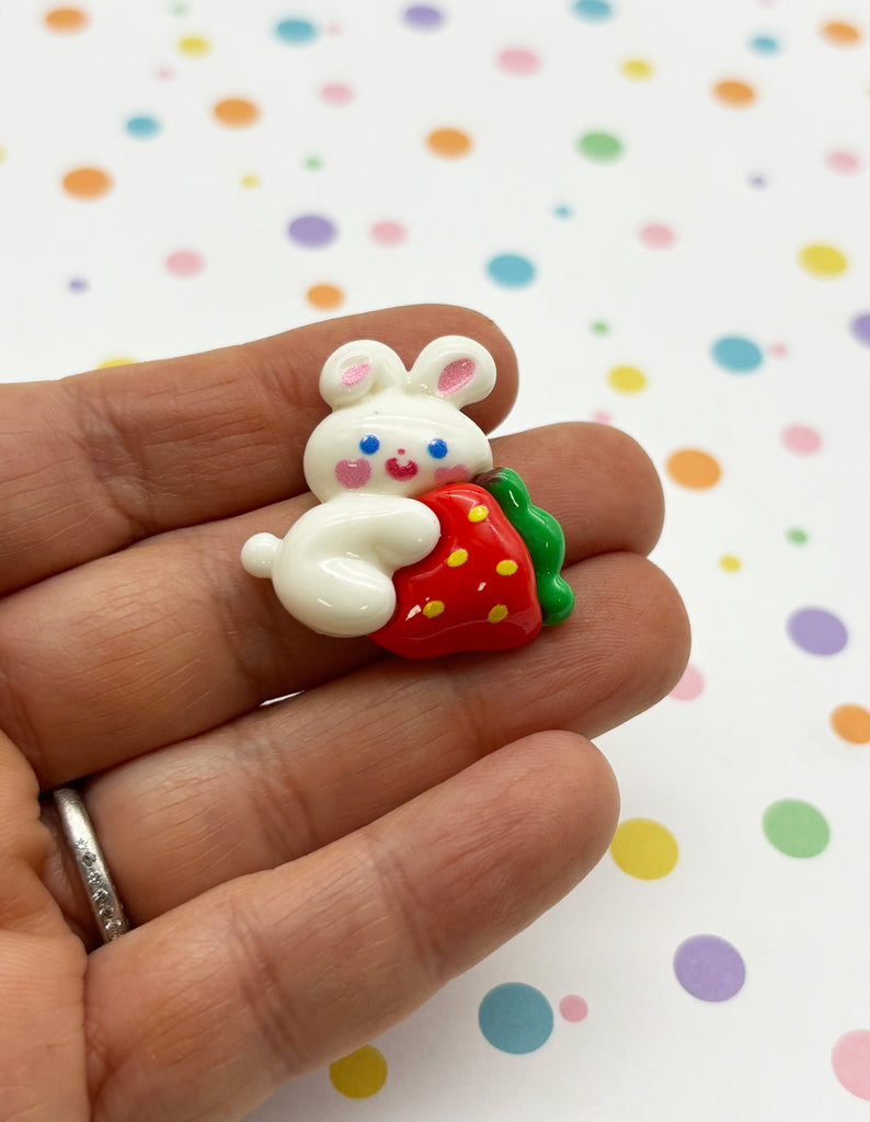 a small toy of a bunny holding a strawberry