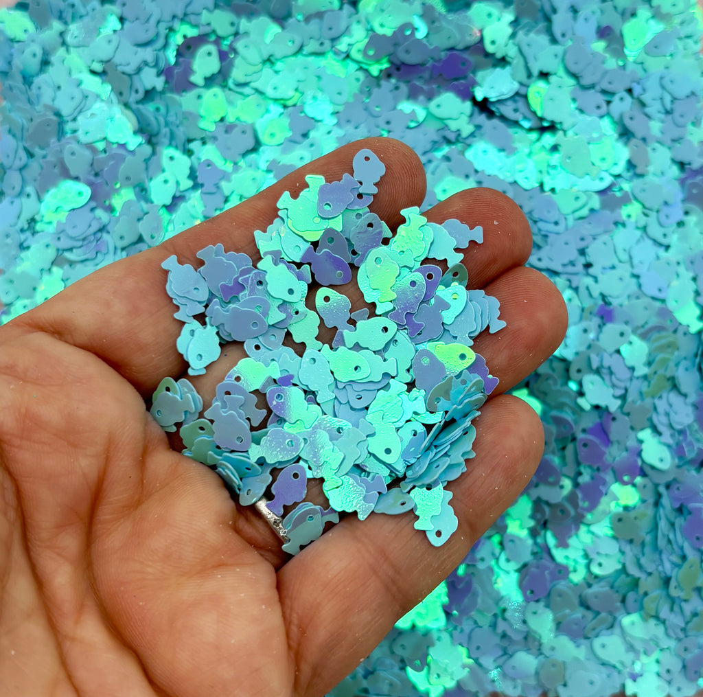 a hand holding a pile of blue and green confetti