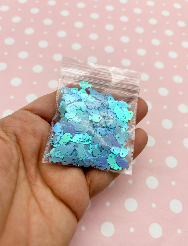 a hand holding a bag of blue and green confetti