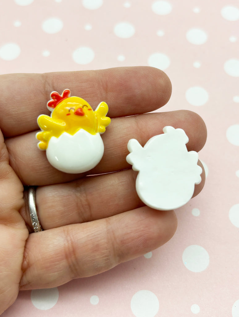 a hand holding a tiny toy chicken and an egg
