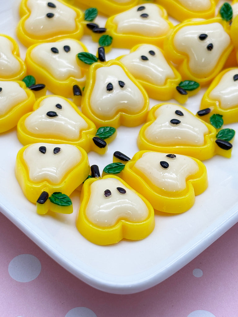a white plate topped with lots of yellow ghost cookies