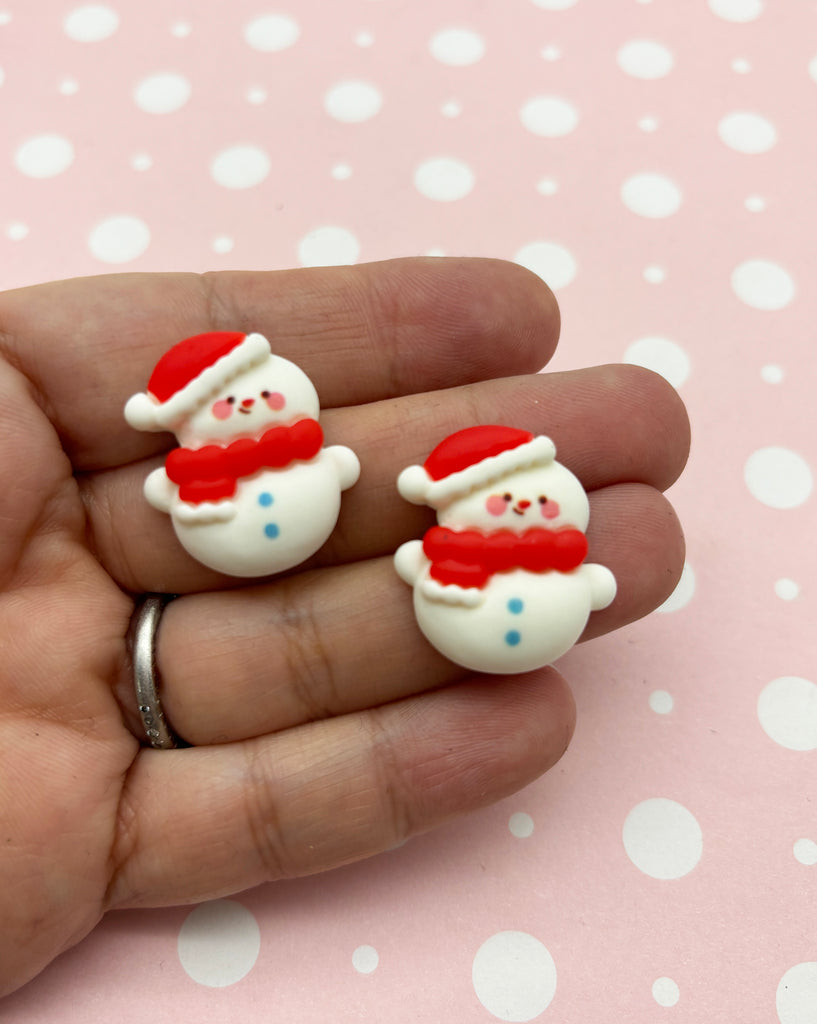a hand holding a pair of christmas themed earrings