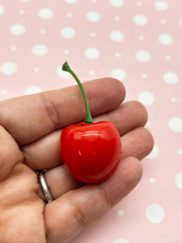 a tiny red cherry in a persons hand