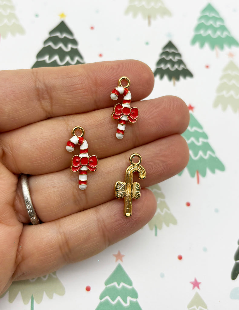 a person holding three christmas charms in their hand