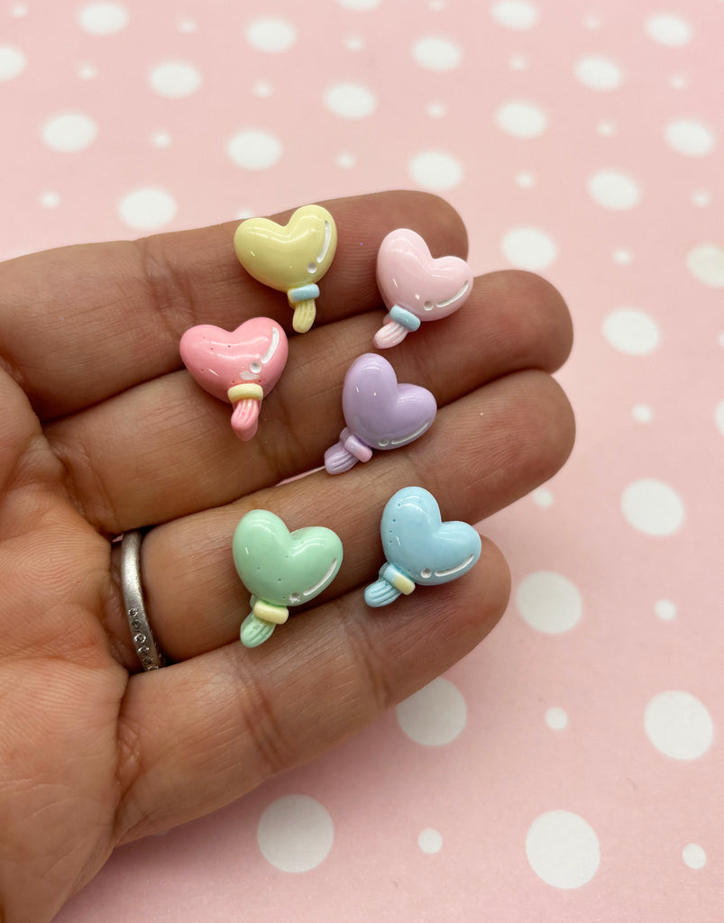 a person's hand holding five small heart shaped rings