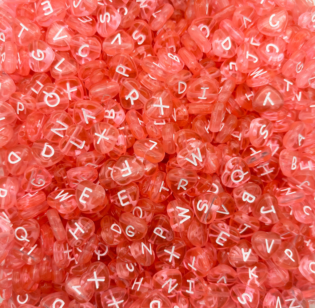 a pile of pink beads with white letters on them