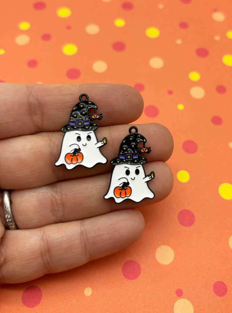 a hand holding two halloween ghost earrings