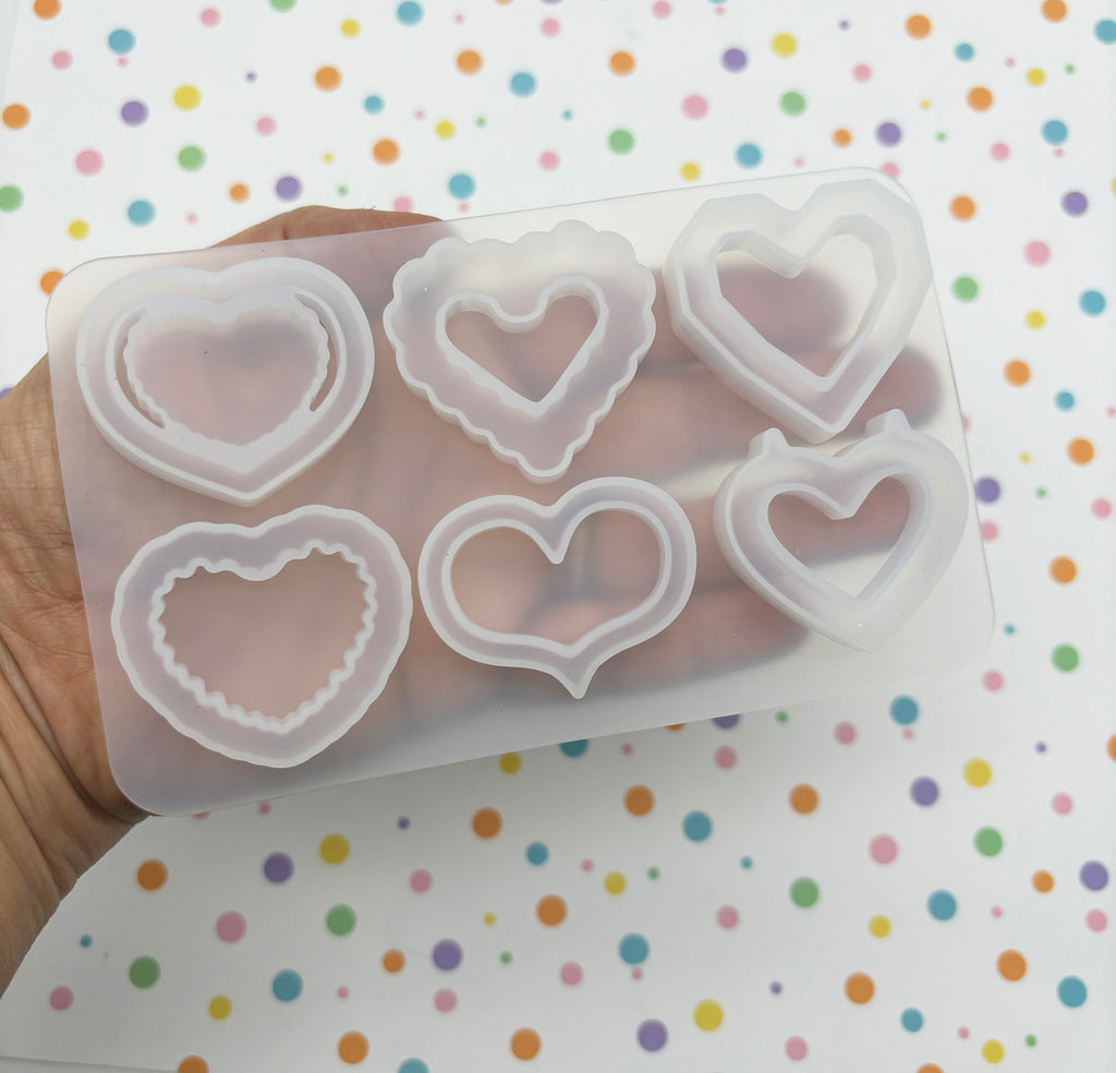 a hand holding a set of heart shaped cookie cutters
