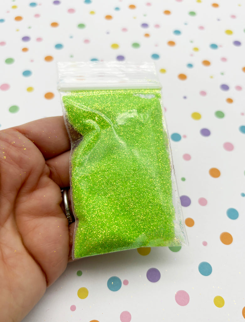 a hand holding a bag of green glitter